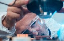 Ein älterer Wissenschaftler arbeitet an einem optischen Gerät