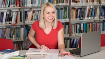 Eine Doktorandin in der Bibliothek beim Schreiben der Doktorarbeit
