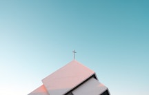 Das Dach einer Kirche mit einem Kreuz als Symbolbild für die Kirche als Arbeitgeber