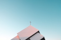 Das Dach einer Kirche mit einem Kreuz als Symbolbild für die Kirche als Arbeitgeber