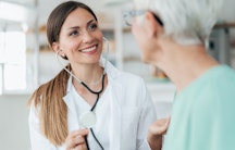 Eine lächelnde Assistenzärztin im Gespräch mit einer Patientin