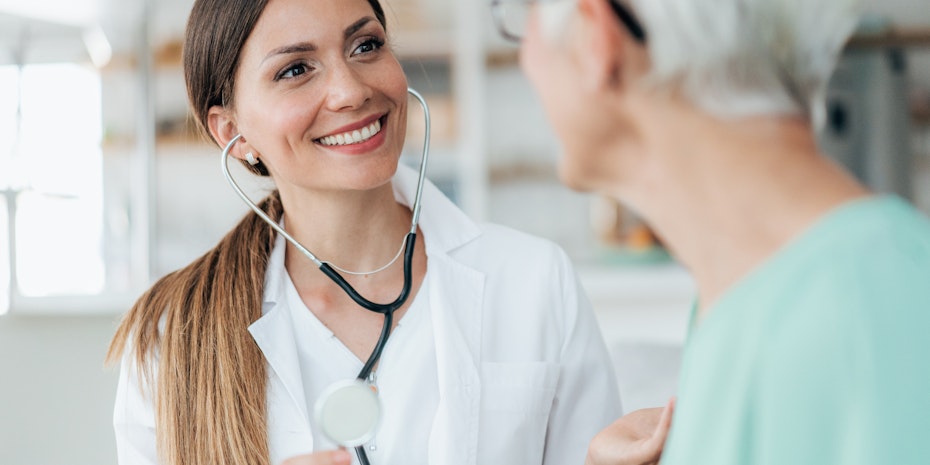Eine lächelnde Assistenzärztin im Gespräch mit einer Patientin