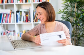 Frau am Computer mit einem Bewerbungsschreiben in der Hand