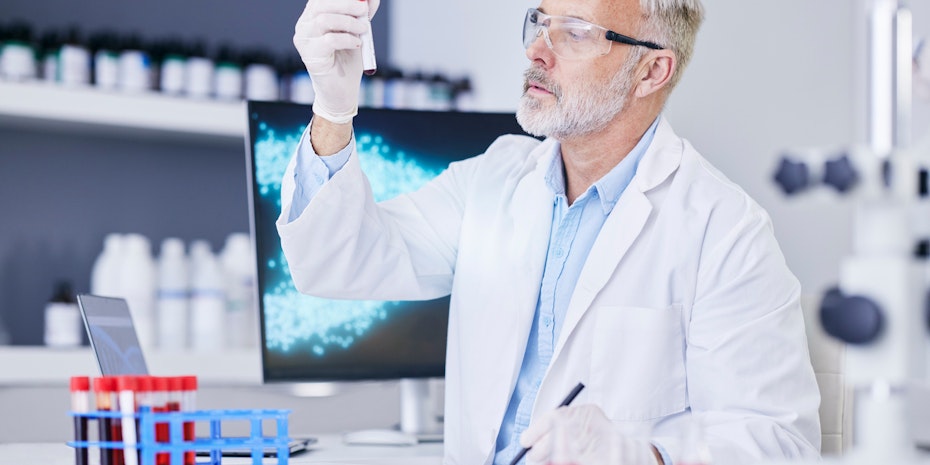 Ein Biotechnologe blickt prüfend auf eine Probe