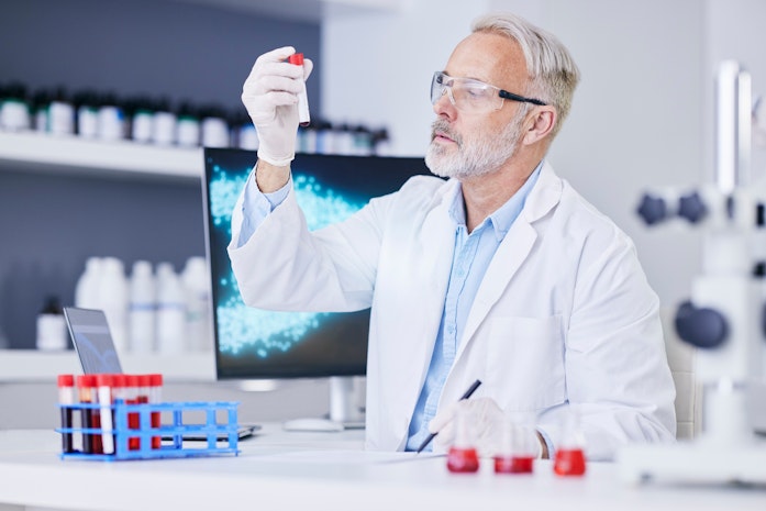 Ein Biotechnologe blickt prüfend auf eine Probe