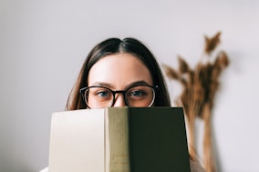 Germanistik: Eine Frau mit Brille schaut hinter einem Buch hervor