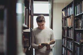 Ein Linguist blättert in einem Buch in einer Bibliothek