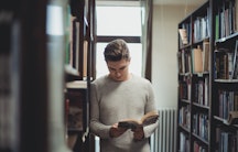 Ein Linguist blättert in einem Buch in einer Bibliothek