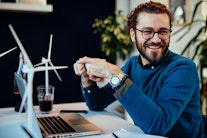 Ein Klimaschutzmanager am Schreibtisch mit Windmühl-Modellen