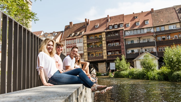 Vier Personen sitzen am Wasser in Erfurt als Symbolbild für das Leben in Erfurt
