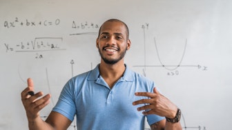 Ein Mathematiker vor einem Whiteboard mit Graphen und Berechnungen