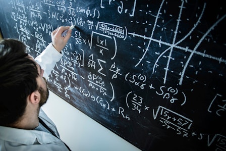 Ein Mathematiker berechnet Formeln an einer Tafel