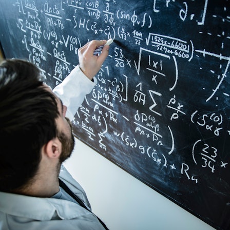 Ein Mathematiker berechnet Formeln an einer Tafel