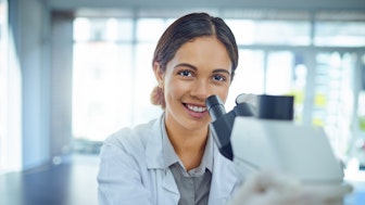 Eine junge Postdoktorandin am Mikroskop im Labor
