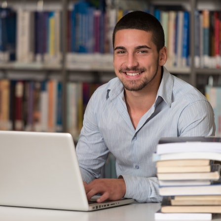 Ein Doktorand in einer Bibliothek am Laptop