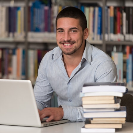 Ein Doktorand in einer Bibliothek am Laptop