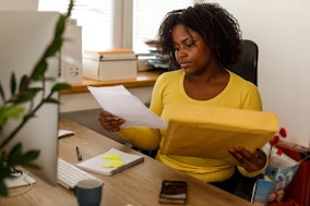 Unterlagen nachreichen: Geschäftsfrau entnimmt Papiere aus einem Umschlag